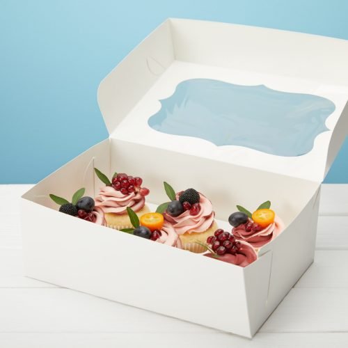 box with cupcakes on white surface isolated on blue